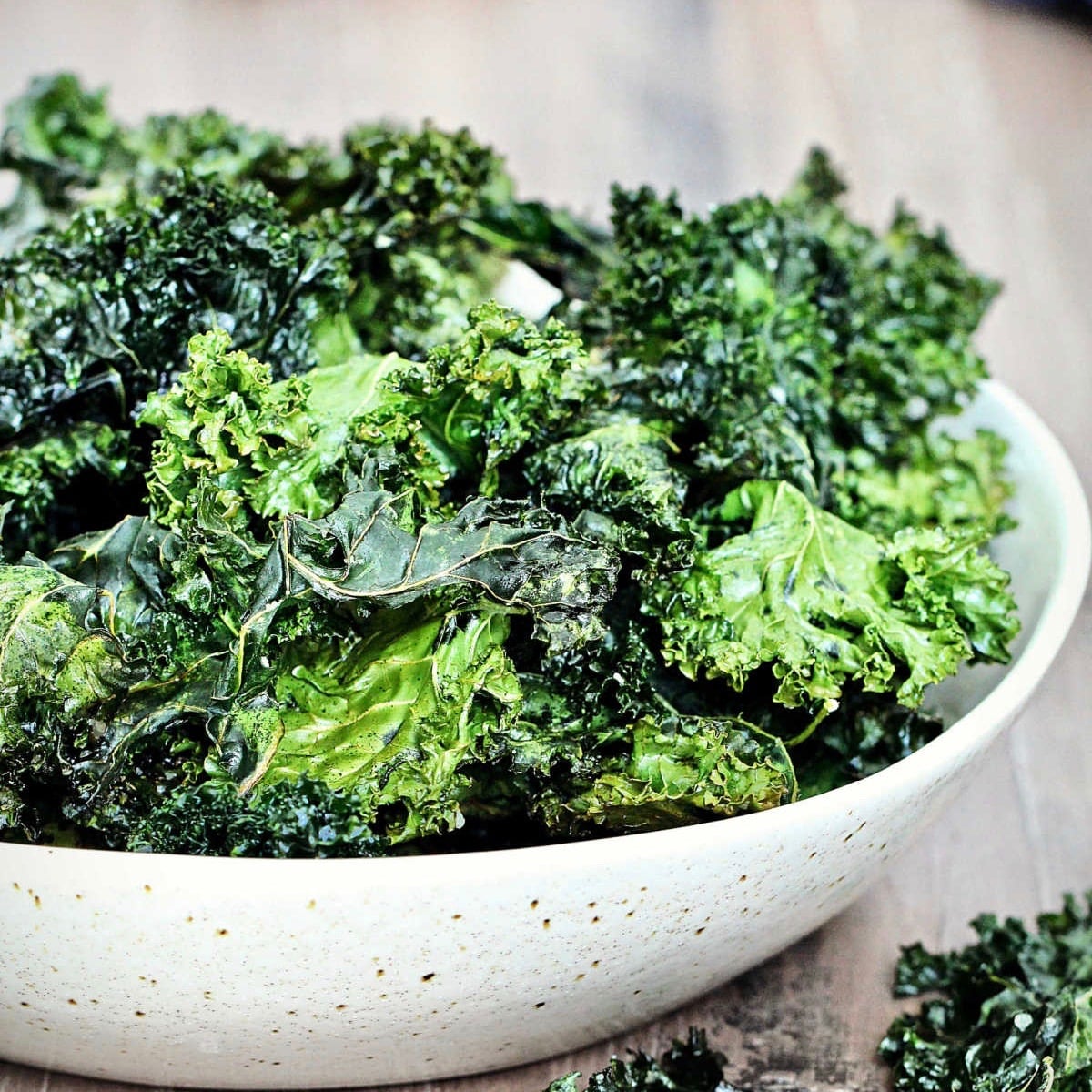 Crispy kale chips in a beige bowl