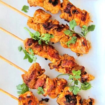 Overhead shot of Tandoori chicken kebabs on a white plate.