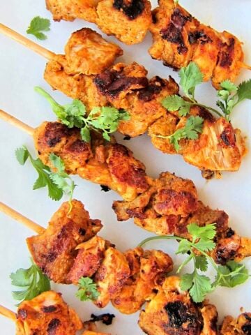 Overhead shot of Tandoori chicken kebabs on a white plate.