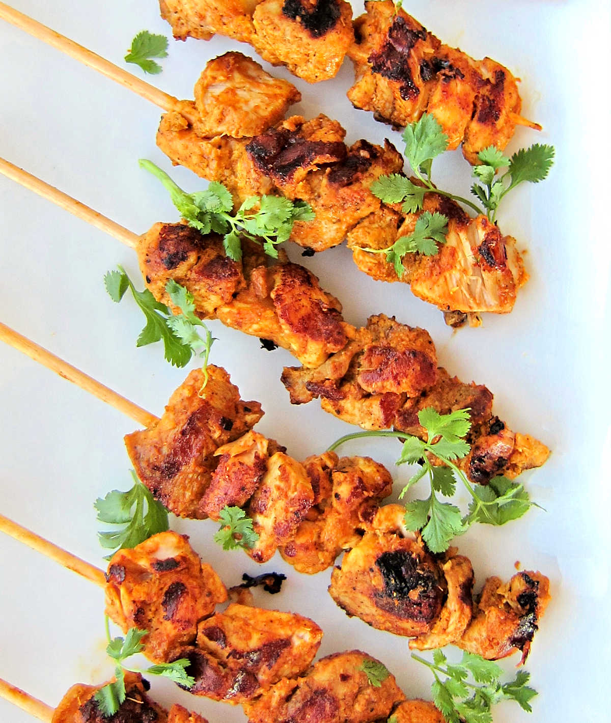 Overhead shot of Tandoori chicken kebabs on a white plate.