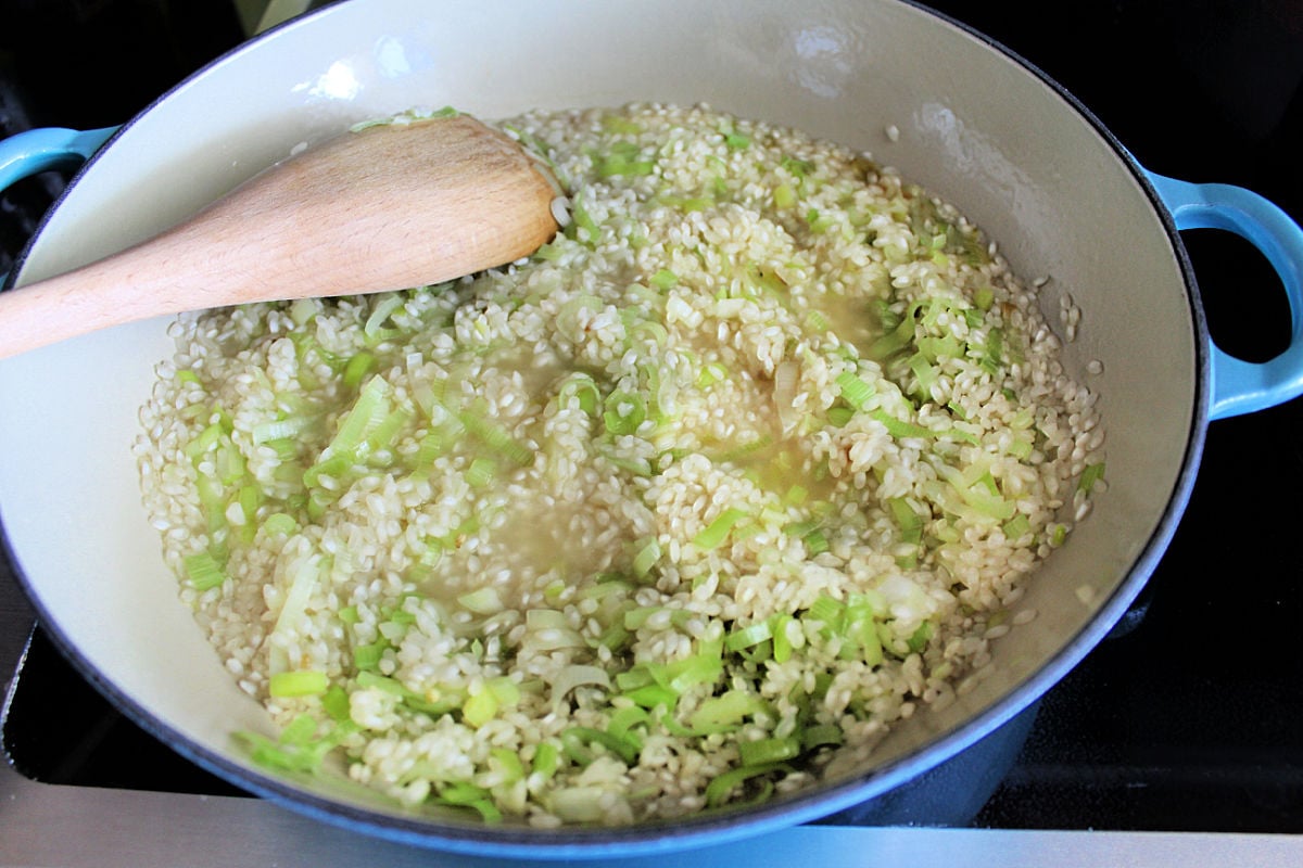 lemon risotto in skillet stirring with a wooden spoon