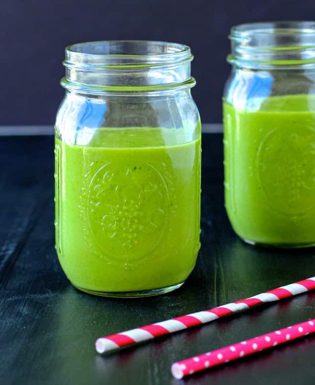 mango and spinach smoothie in two mason jars.