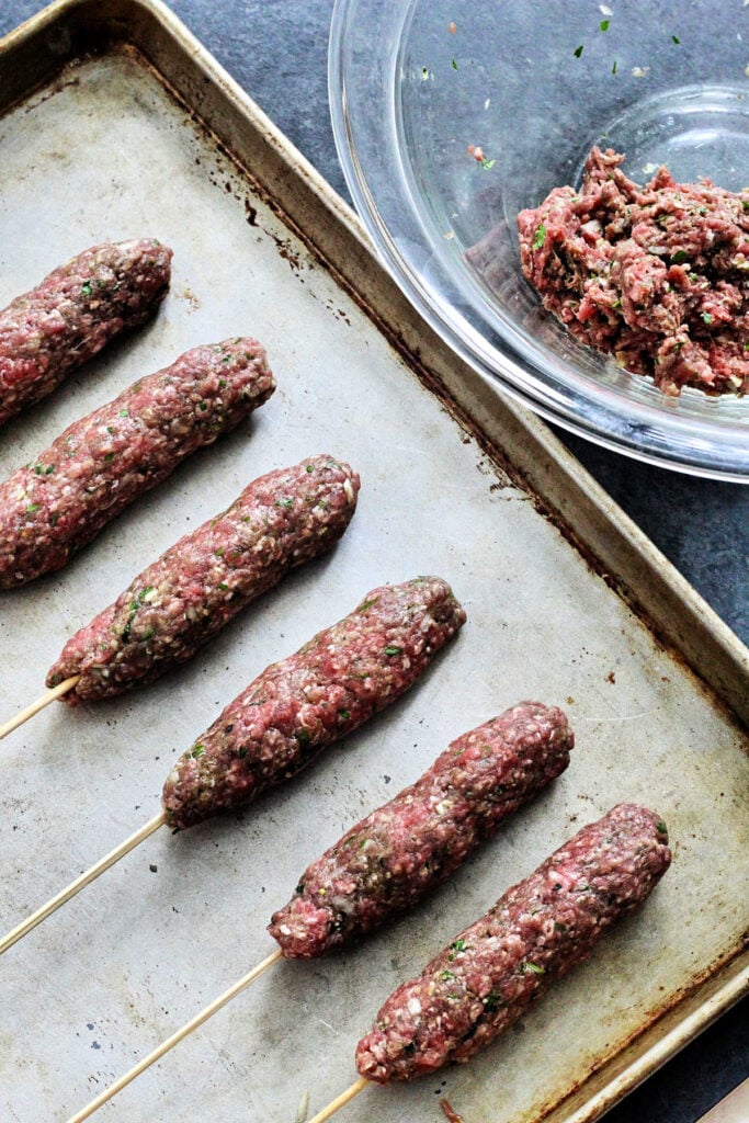 kebabs lined up on a sheet pan