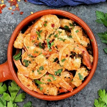 Overhead shot of Spanish garlic shrimp in a brown dish.