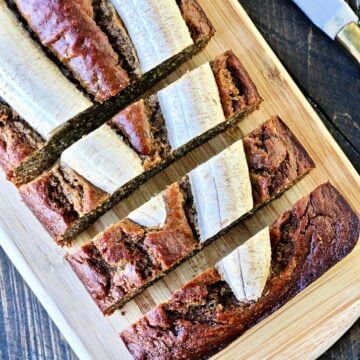 Overhead of sliced banana flax bread on a wooden cutting board.
