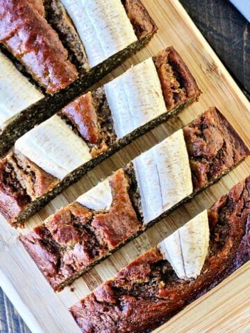 Overhead of sliced banana flax bread on a wooden cutting board.