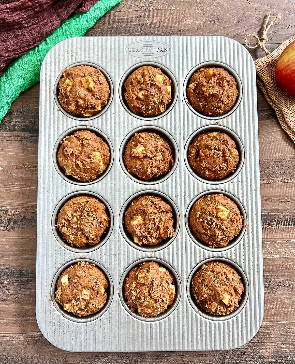 A dozen spiced apple muffins in a muffin pan.