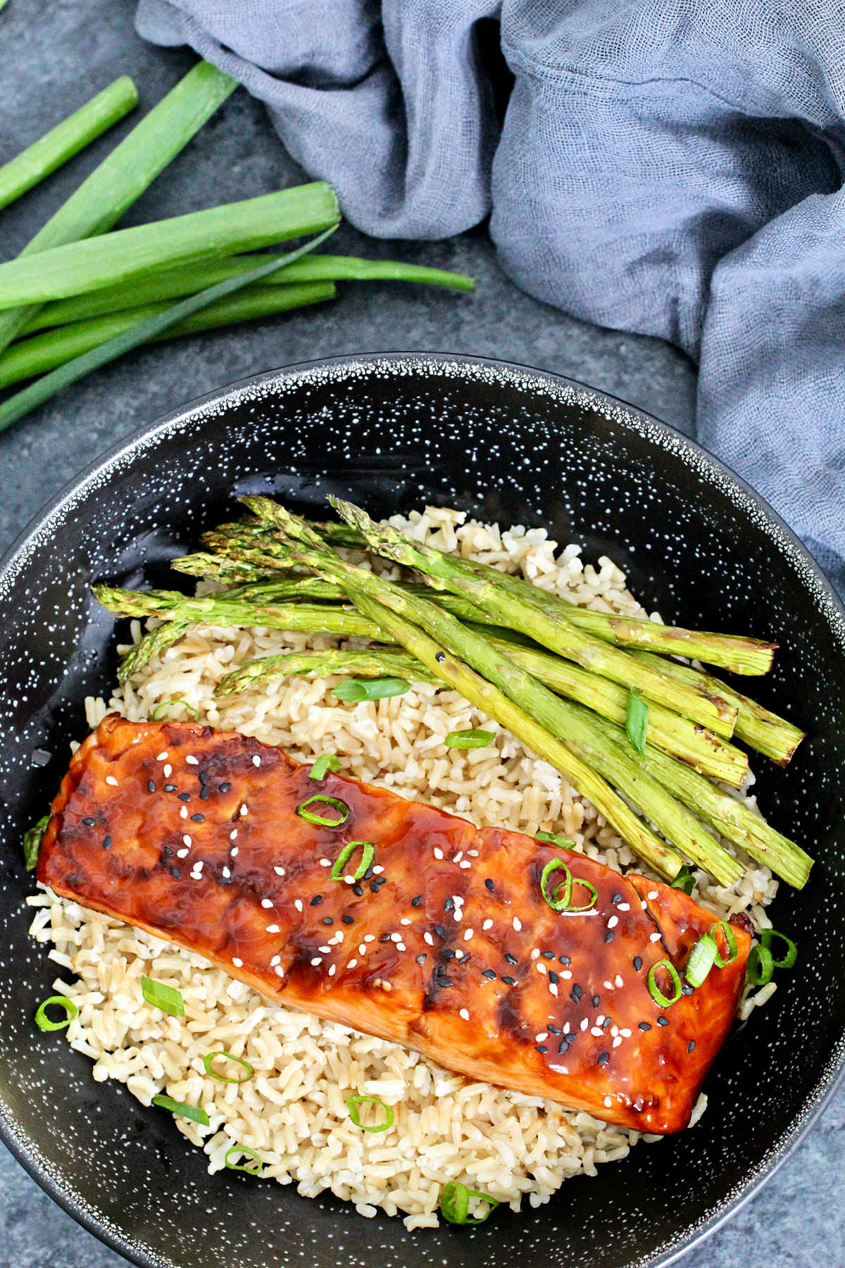 overhead shot of air fryer salmon teriyaki in a bowl with brown rice and asparagus.