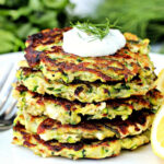 Stack of zucchini fritters with a dollop of yogurt on top.
