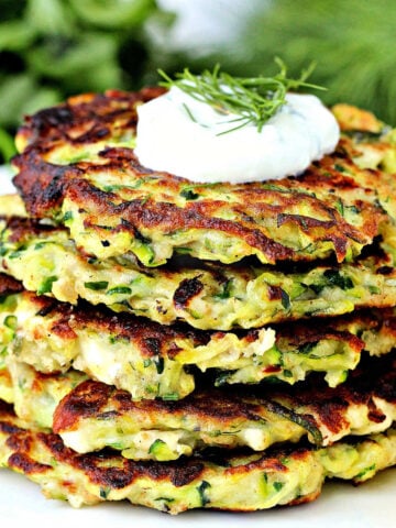 Stack of zucchini fritters with a dollop of yogurt on top.