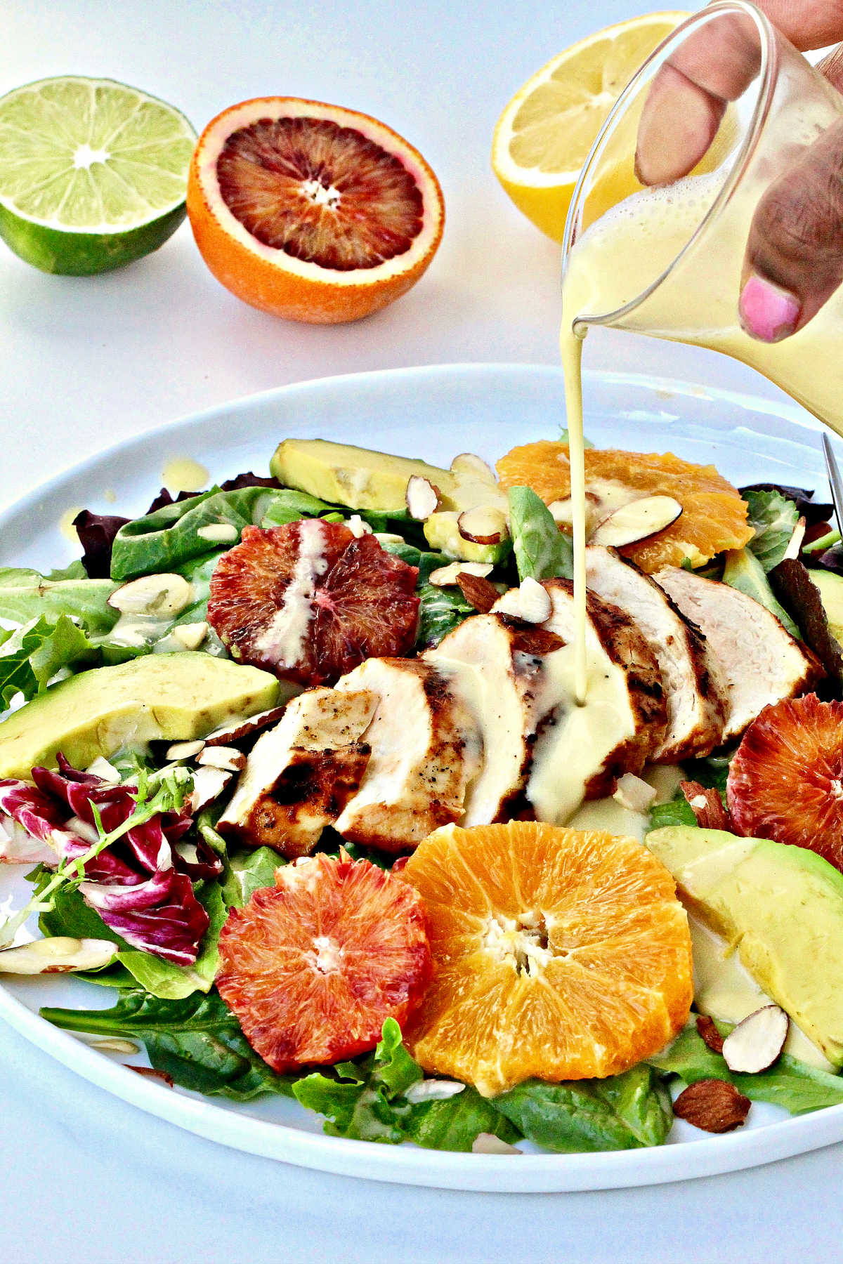 Creamy citrus salad dressing being poured onto salad.