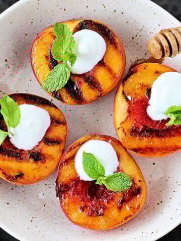 Grilled peaches with Greek yogurt in a white bowl.
