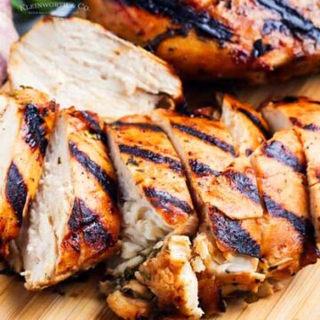 Sliced grilled chicken on a cutting board.