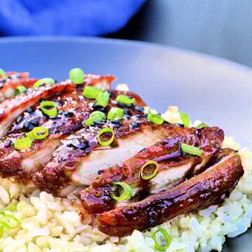 Sliced chicken teriyaki on a bed of brown rice.