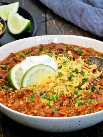 A bowl of turkey chili with shredded cheese and sour cream.