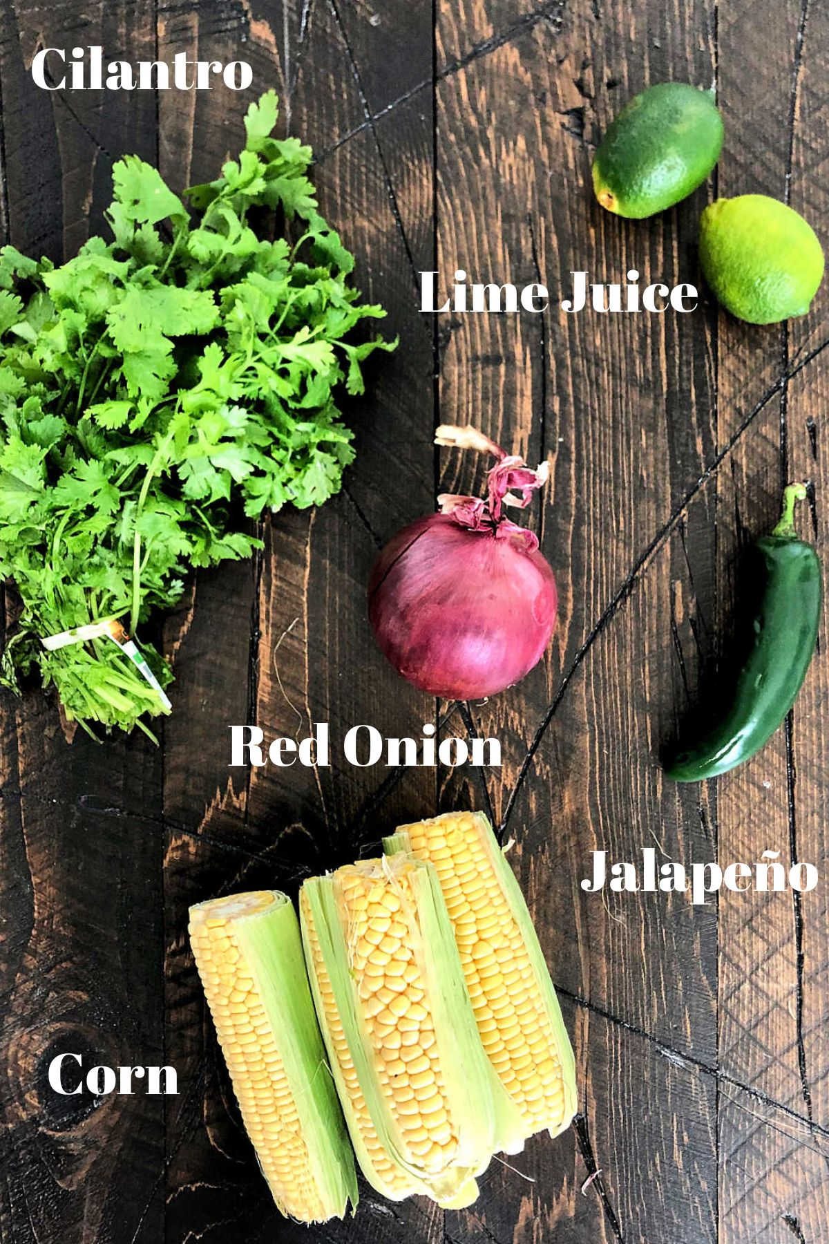 Ingredients for chipotle corn salsa on a brown wooden board.