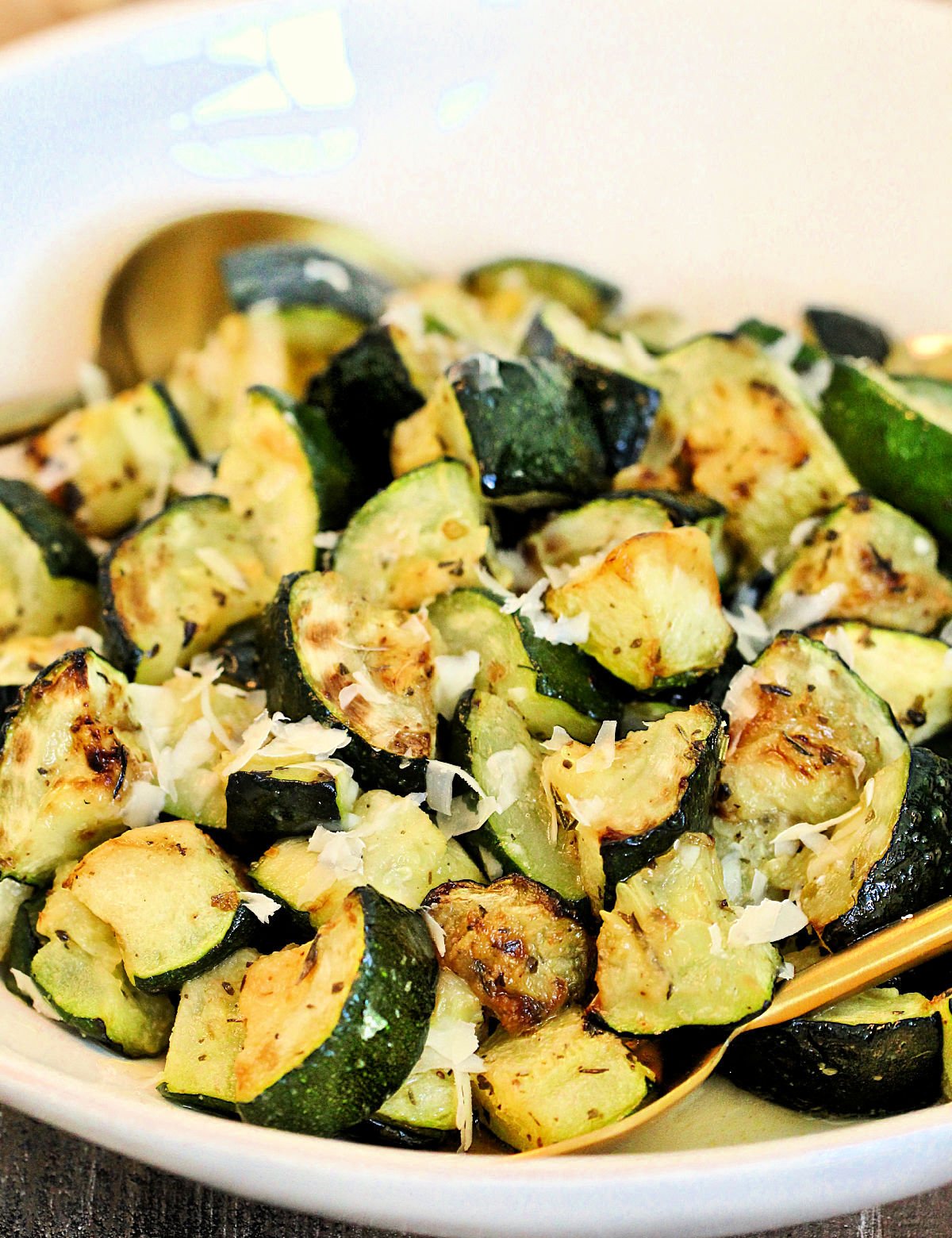 Air fryer zucchini in a white bowl with grated parmesan cheese on top.