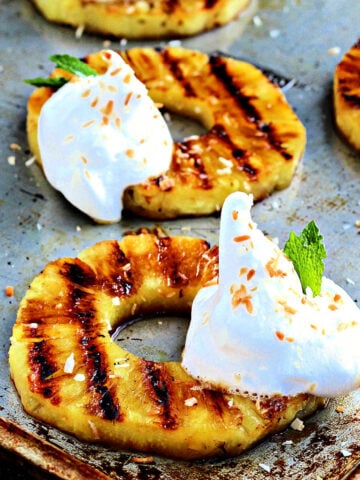 Grilled pineapple rings with dollops of aquafaba whipped cream.