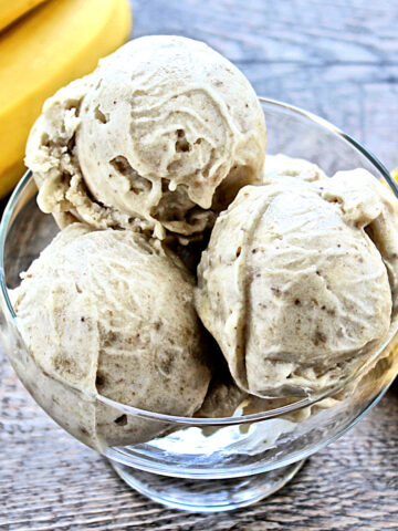 Overhead shot of three scoops of one-ingredient banana ice cream in a glass bowl.