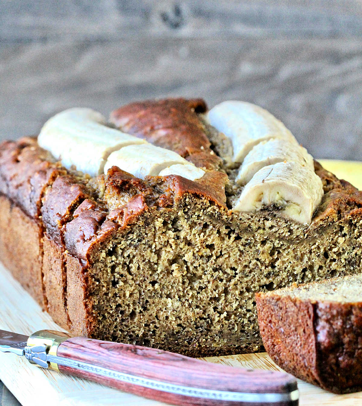 A loaf of banana flaxseed bread with a slice cut off.