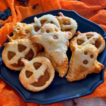 Halloween pumpkin empanadas in a black bowl.