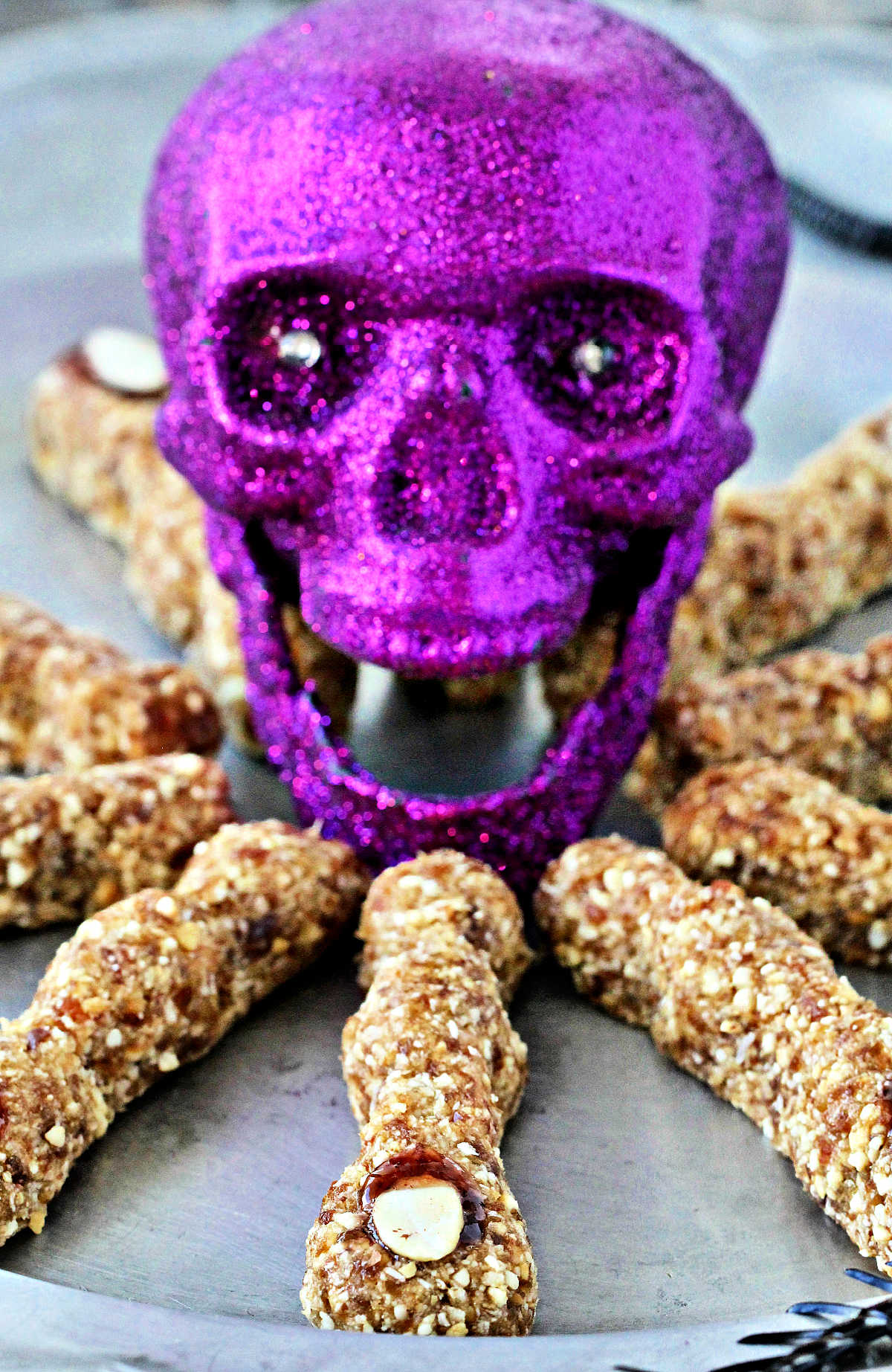 Spooky Witches' Fingers on a silver plate surrounding a purple decorative skull
