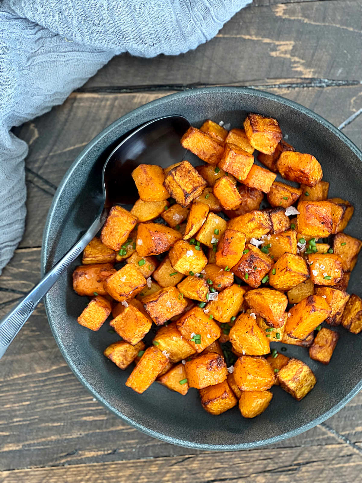 Overhead photo of air fryer butternut squash in a gray bowl with a black spoon in it.