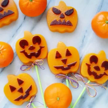 Jack o lantern pumpkin gummies on a marble background.