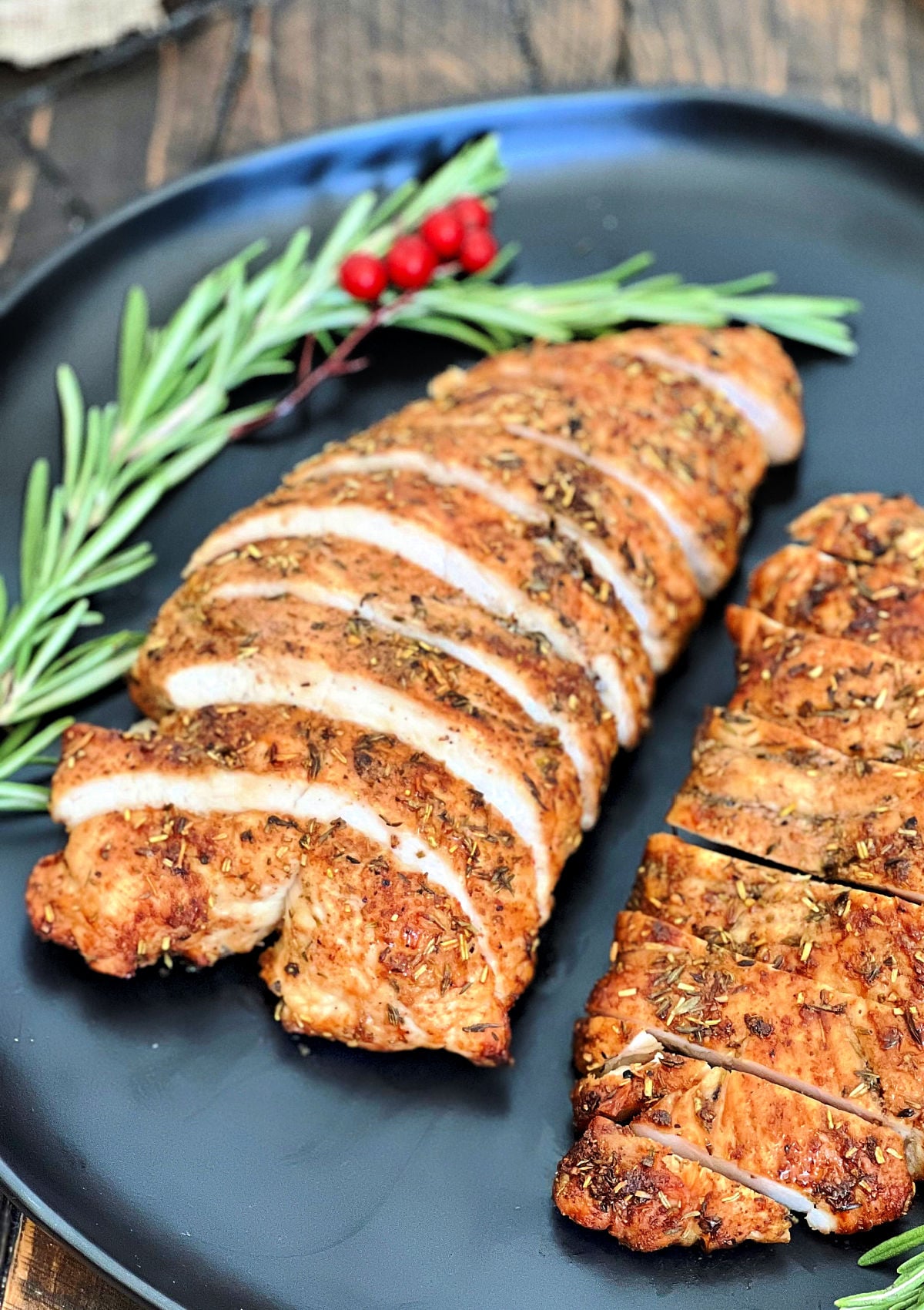 Sliced air fryer turkey tenderloin on a black plate. 