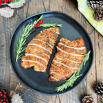 Two turkey tenderloins on a black plate.