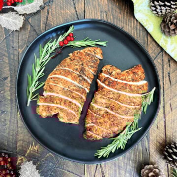 Two turkey tenderloins on a black plate.