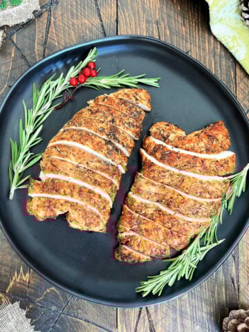 Two turkey tenderloins on a black plate.