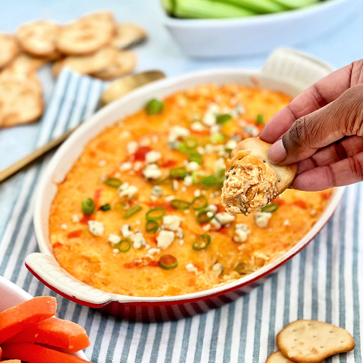 Scooping some buffalo chicken dip up with a cracker.