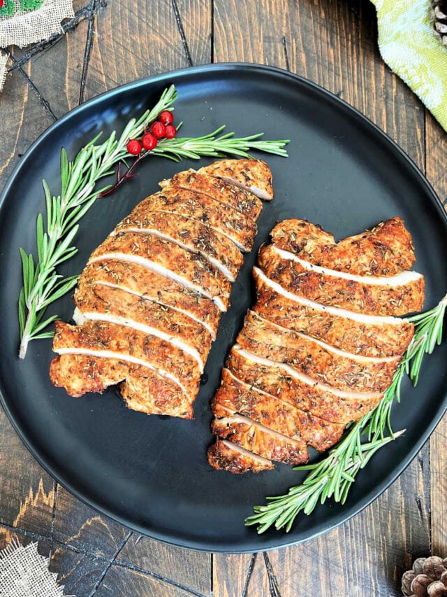 Two turkey tenderloins on a black plate.
