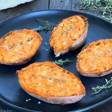 Twice-baked sweet potatoes on a black plate.
