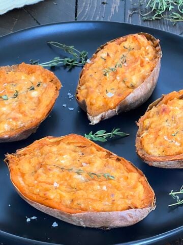 Twice-baked sweet potatoes on a black plate.