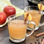 A glass of crock pot mulled cider with a cinnamon stick.