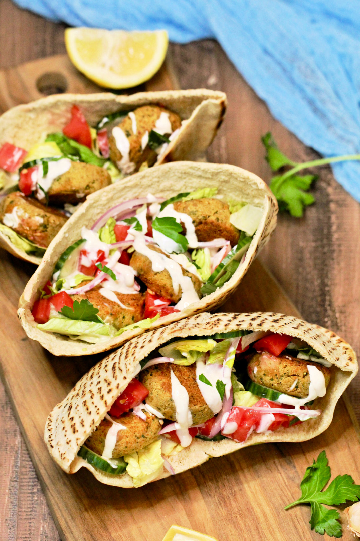 3 falafel pita sandwiches on wood board.