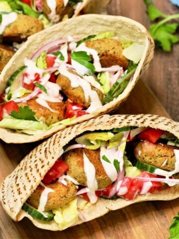 3 falafel pita sandwiches on wood board.