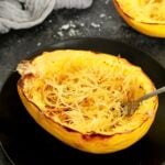 A spaghetti squash boat on a black plate.