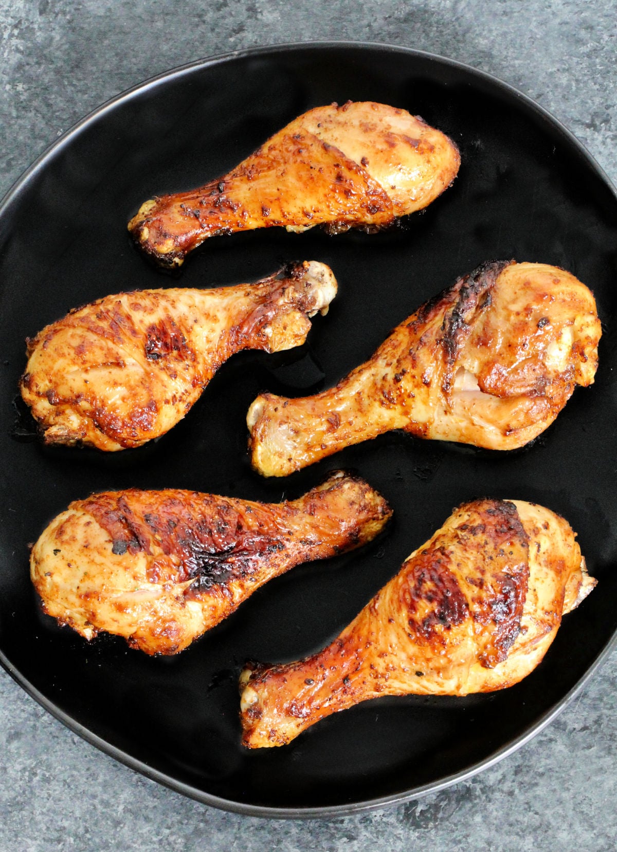 Air fryer chicken legs on black plate.