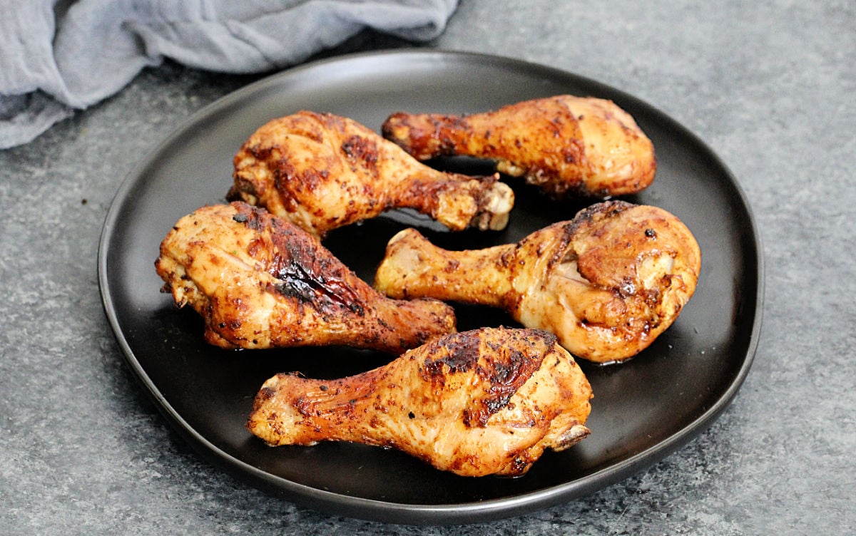 Air fryer chicken legs on black plate.