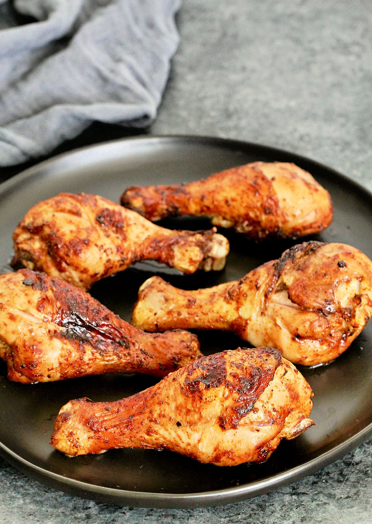 Air fryer chicken legs on black plate.