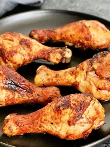 Air fryer chicken legs on black plate.