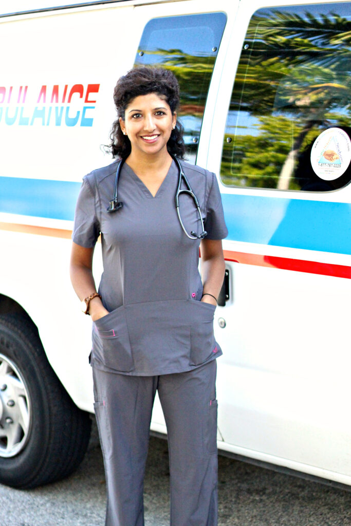 The Foodie Physician, Dr. Sonali Ruder wearing gray scrubs standing in front of an ambulance.