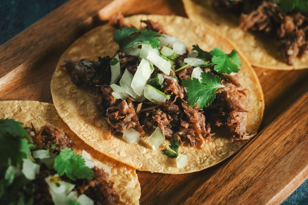 Barbacoa vs. carnitas- tacos on a wooden board.