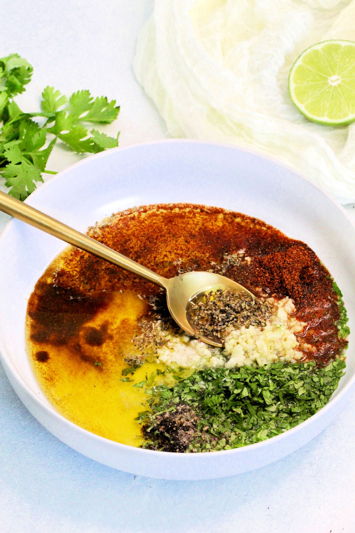 Mexican chicken marinade in white bowl with gold spoon.