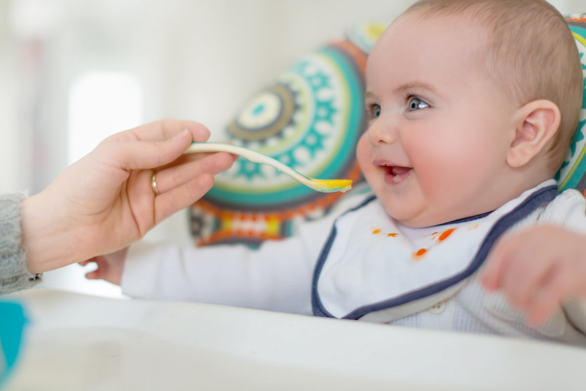A cute baby being fed a spoonful of pureed baby food