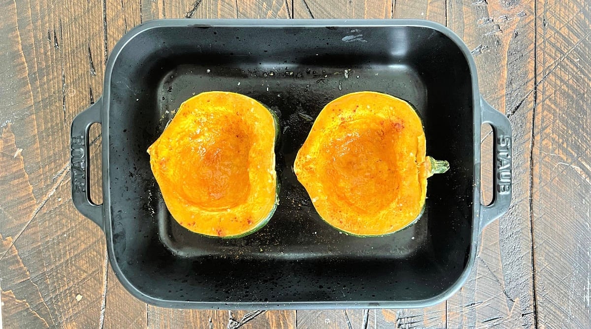 Microwaved acorn squash in a black baking dish.