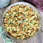 Classic Sage Stuffing in a copper pan with sage, a metal spoon and a brown napkin around it.